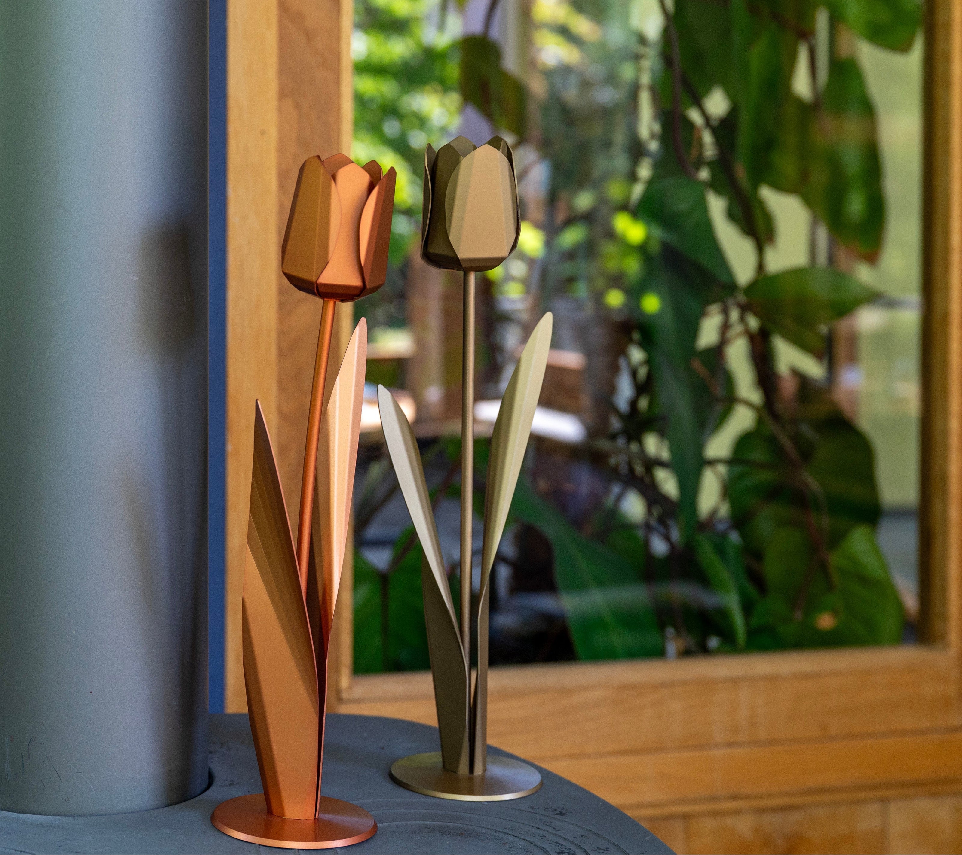 Bronskleurige en goudkleurige metalen tulpen als decoratie bij een raam