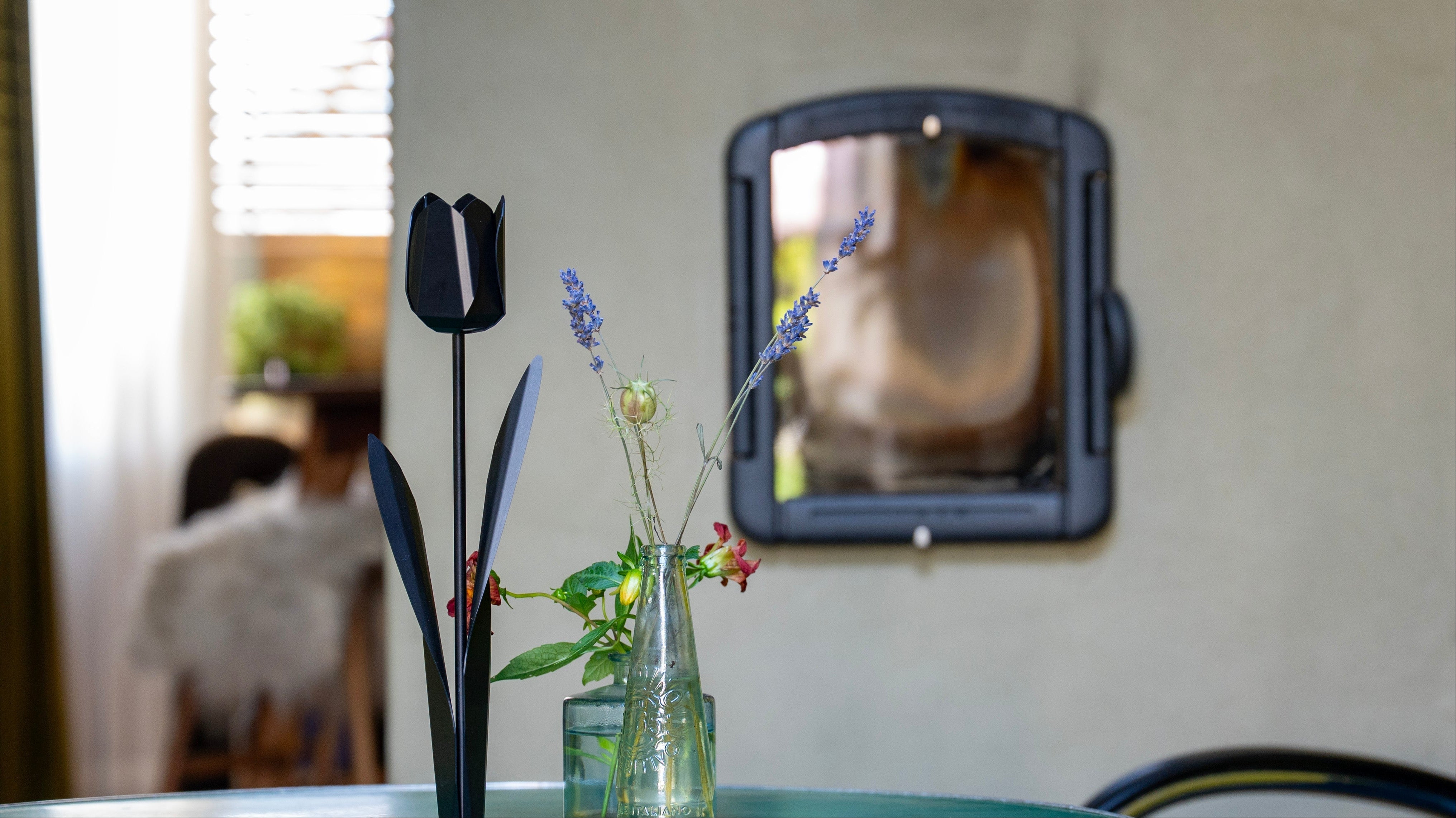 Zwarte metalen tulp als moderne woondecoratie naast een vaas met bloemen