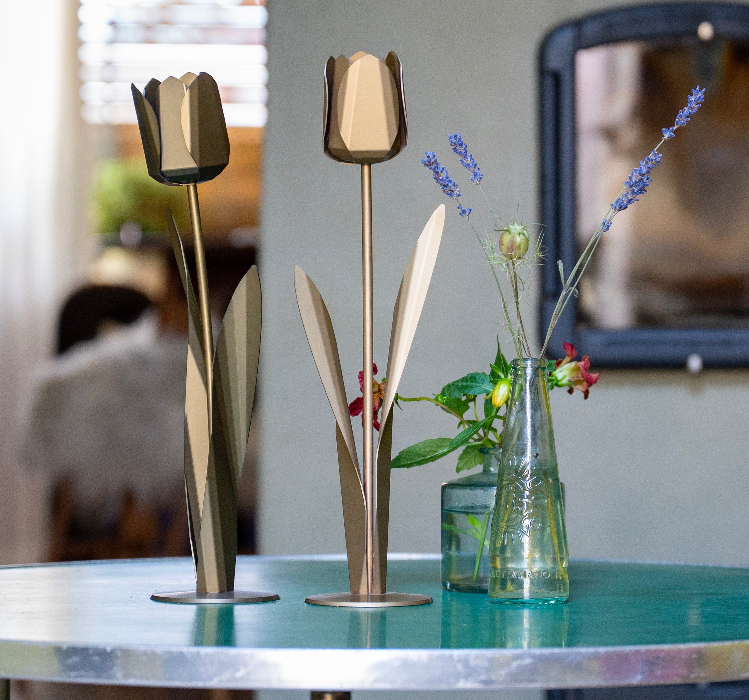 Gunmetalkleurige en goudkleurige metalen tulpen naast een vaas met bloemen als stijlvol en blijvend cadeau